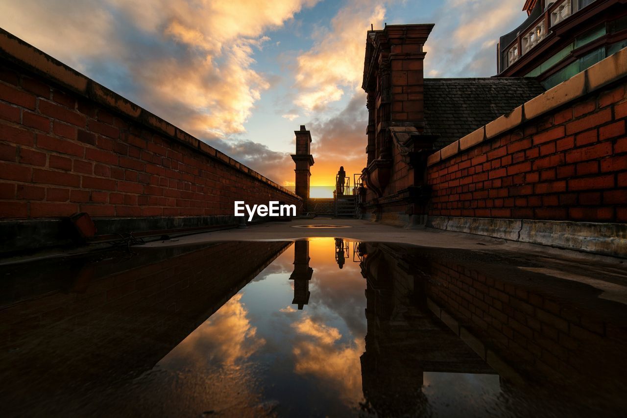 Reflection of building on puddle during sunset