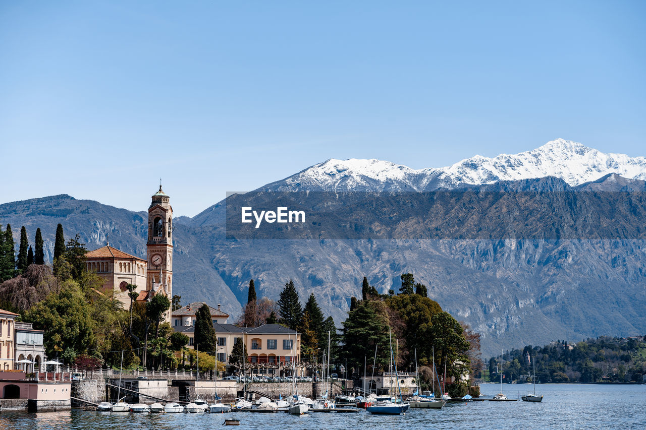 PANORAMIC VIEW OF TREES AND BUILDINGS AGAINST MOUNTAINS