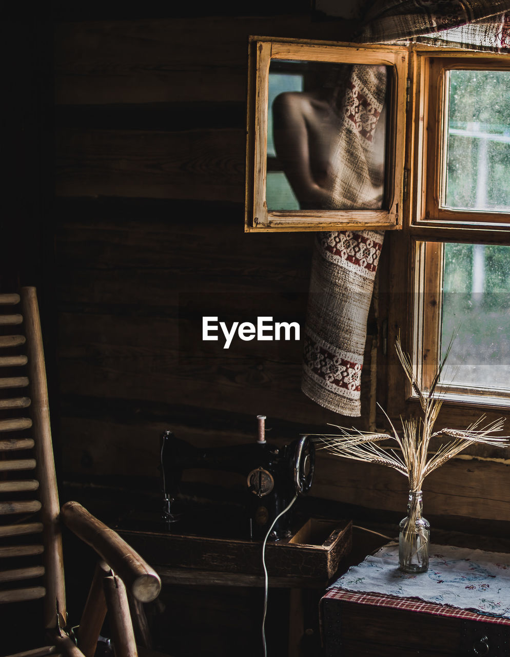 Shirtless woman reflecting on mirror by window at home