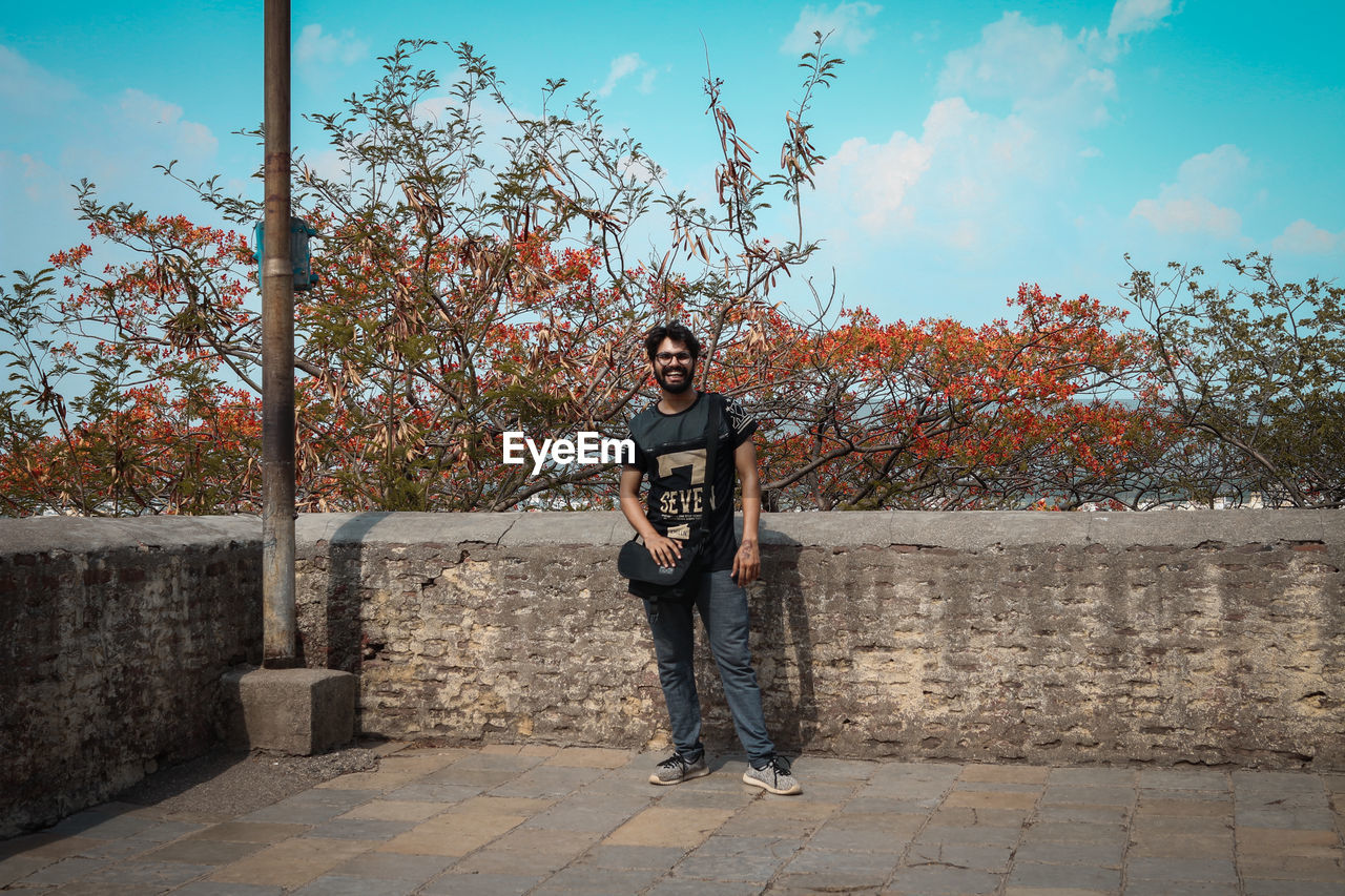 Full length of man standing by tree against sky