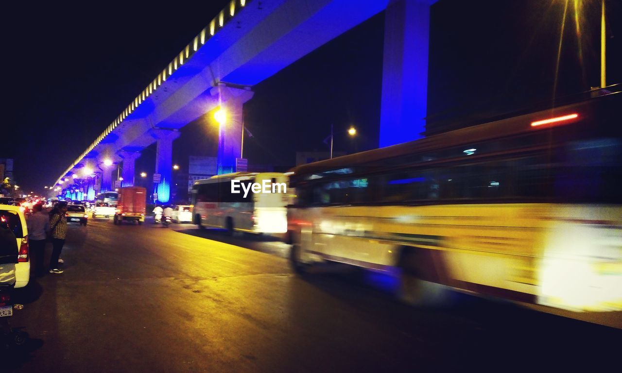 Vehicles moving on illuminated street at night