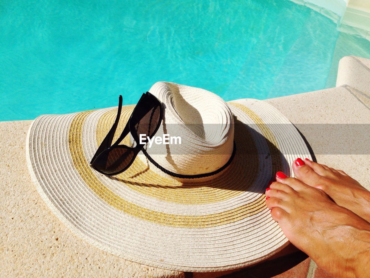 Low section of woman by hat and sunglass at poolside