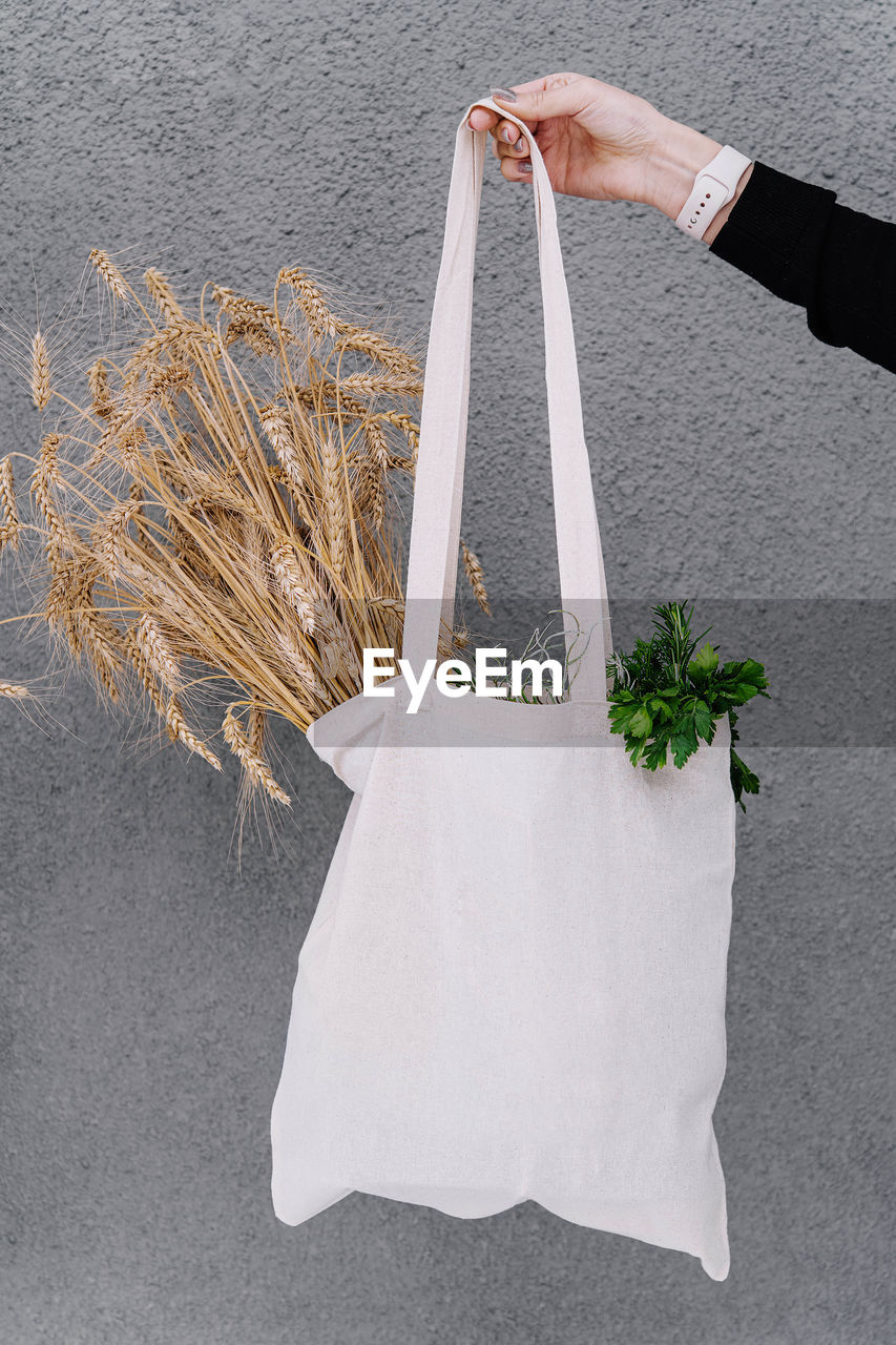 cropped hand of woman holding flower on table