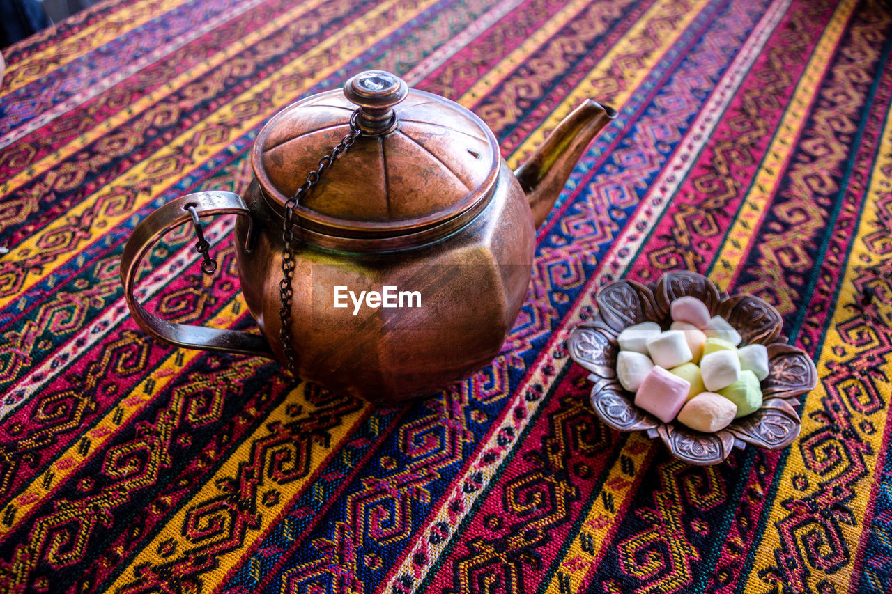 Close-up of tea kettle and candies in bowl on table