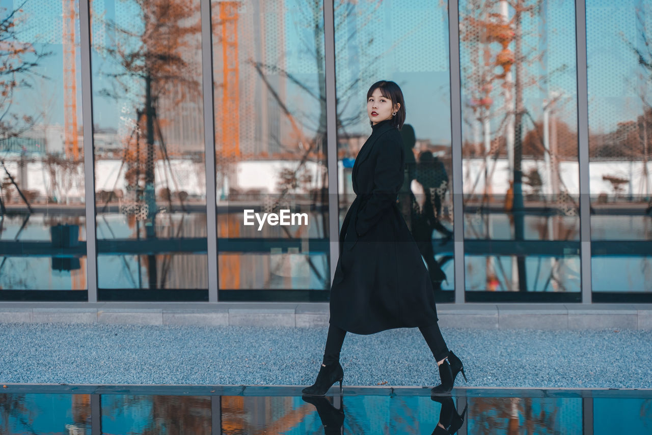 Portrait of woman standing against window