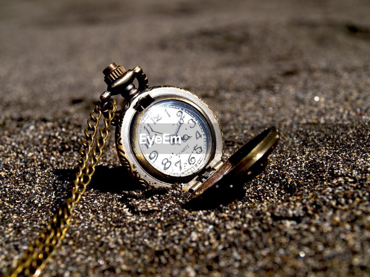 Close-up of pocket watch on sand