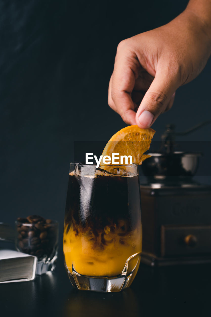 CLOSE-UP OF HAND HOLDING GLASS OF JUICE