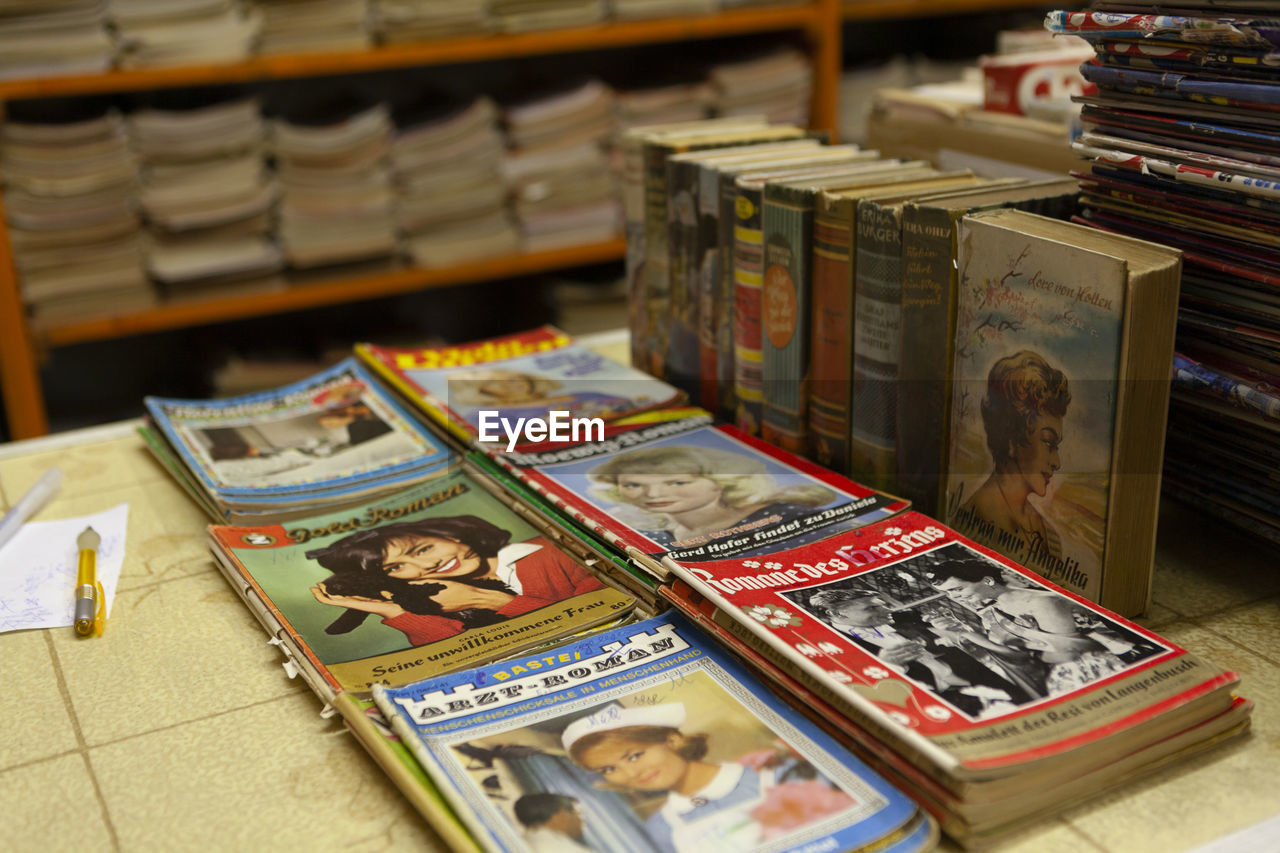 HIGH ANGLE VIEW OF OPEN BOOK ON TABLE IN SHELF