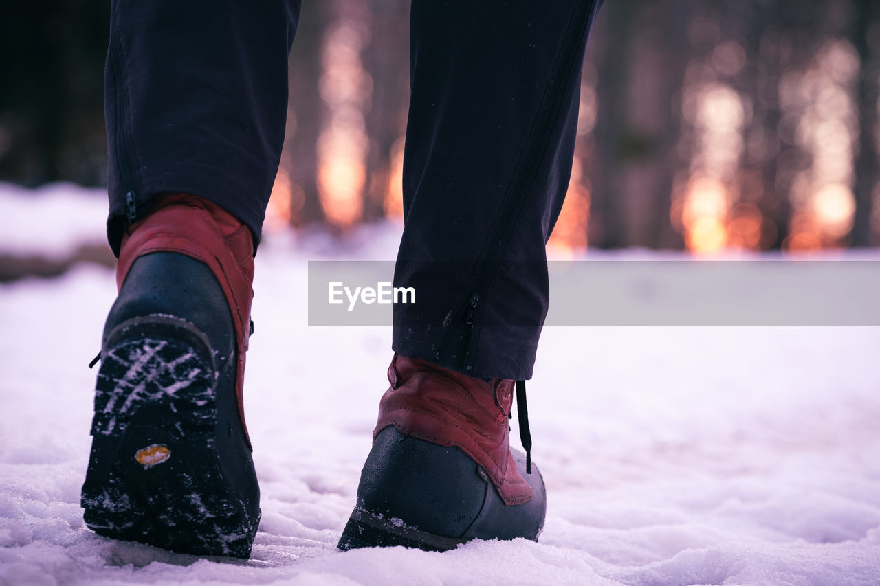 Low section of man walking on snow