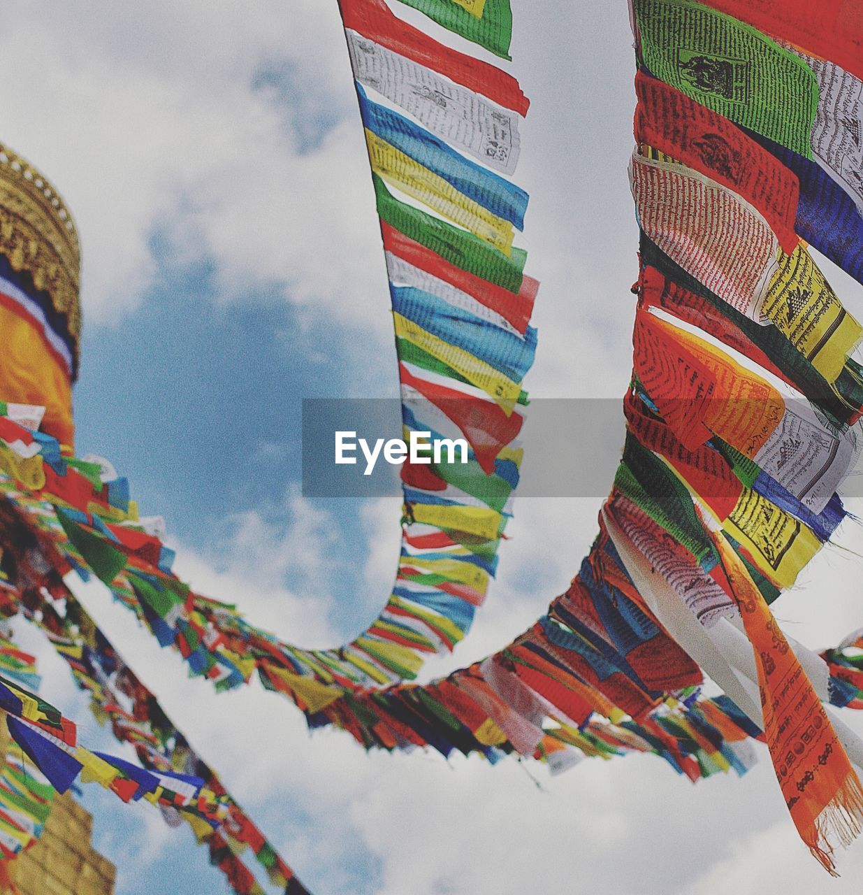 LOW ANGLE VIEW OF COLORFUL FLAGS IN TEMPLE AGAINST SKY