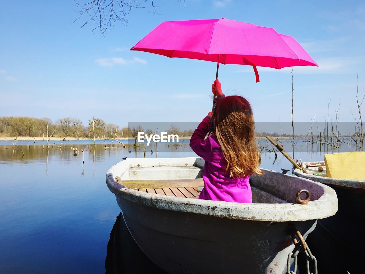 Rear view of girl holding umbrella while sitting in boat