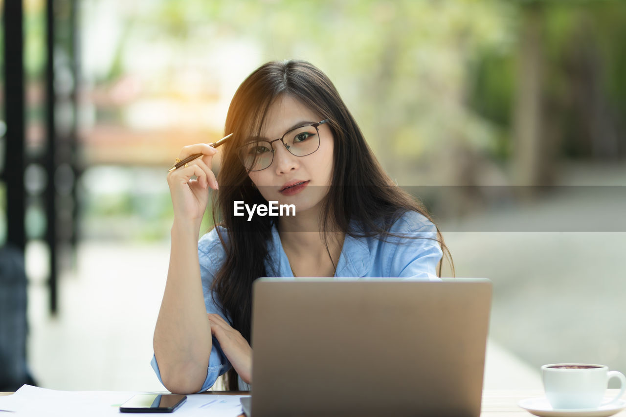 young woman using laptop while sitting at cafe