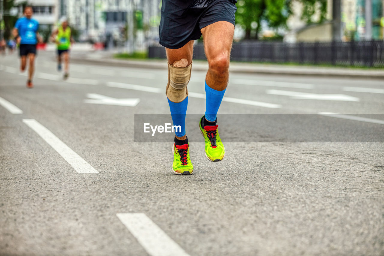 Legs runner man in compression socks and knee pads run race down street