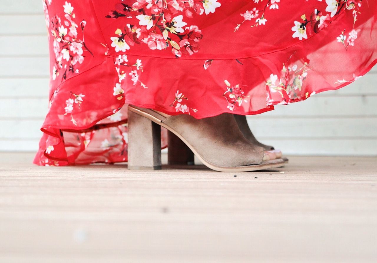 Low section of woman wearing high heels while standing on hardwood floor