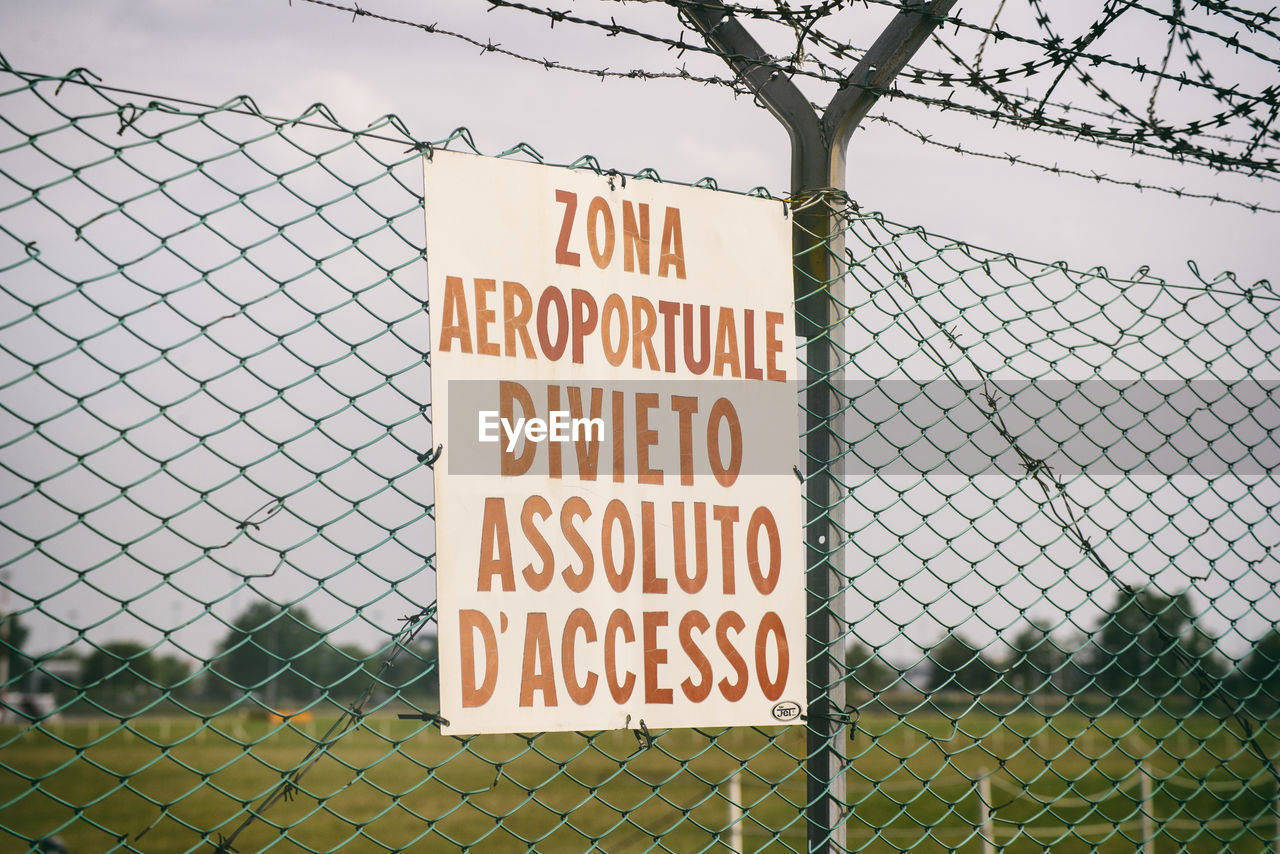 fence, chainlink fence, communication, sign, text, security, western script, protection, wire fencing, chain-link fencing, warning sign, no people, forbidden, day, nature, wire, information sign, sky, outdoors, home fencing, barbed wire, outdoor structure, architecture, plant, wire mesh, metal