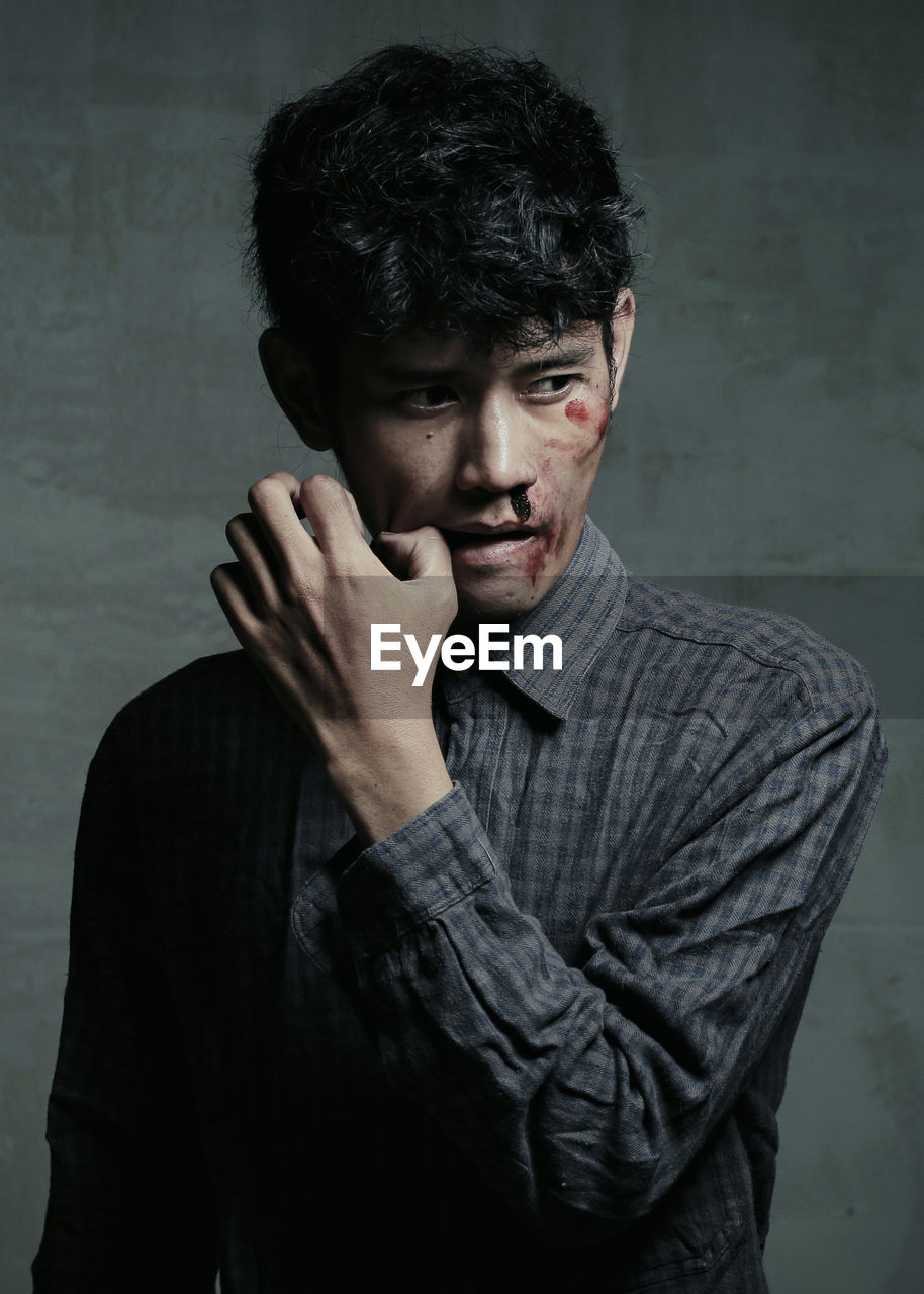 Thoughtful injured young man standing against wall