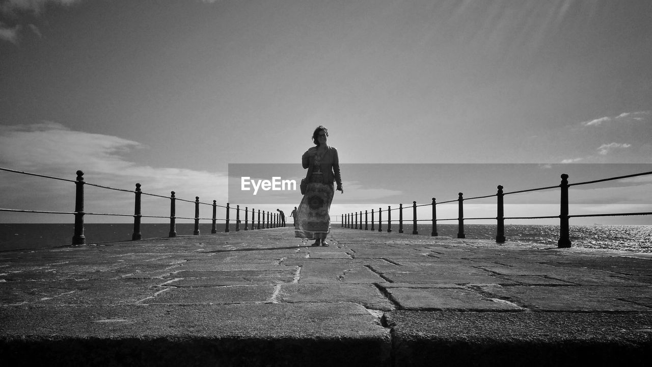 Full length of woman standing on pier over sea against sky