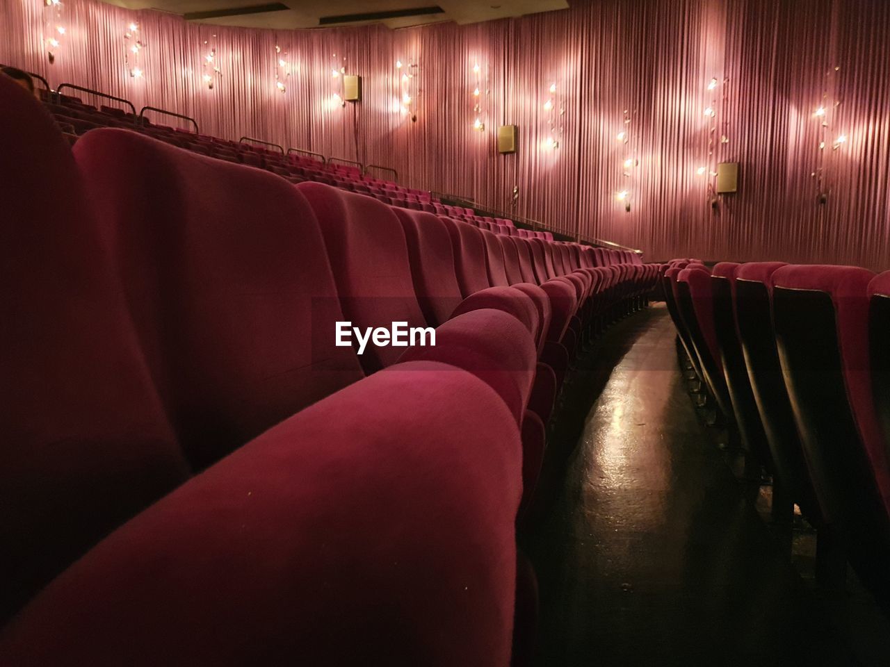 arts culture and entertainment, seat, indoors, movie theater, in a row, auditorium, stage theater, red, lighting equipment, no people, illuminated, stage, darkness, chair, light