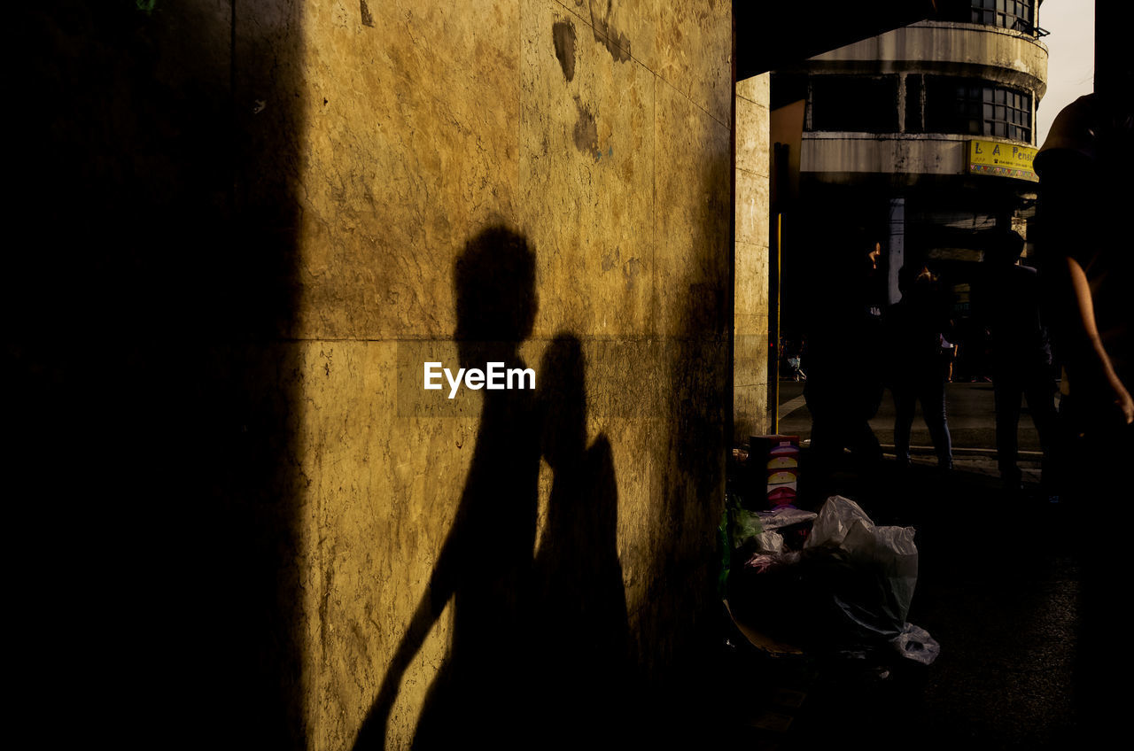 SHADOW OF PEOPLE WALKING ON STREET IN CITY