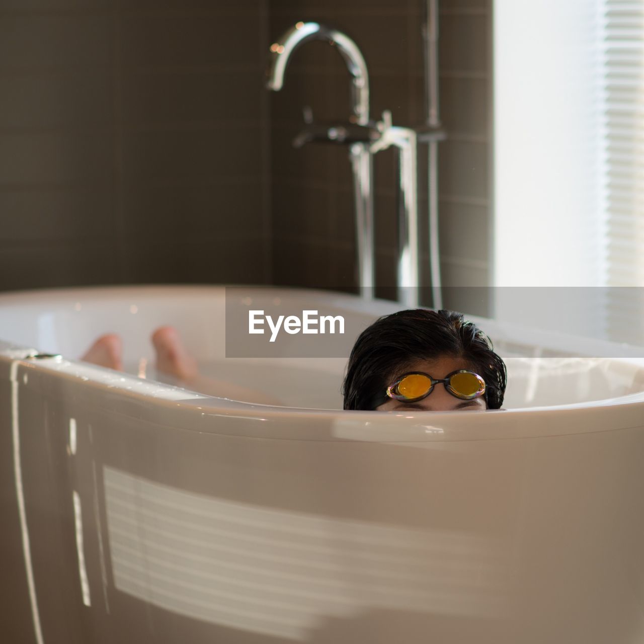 Woman in bathtub with swimming goggles