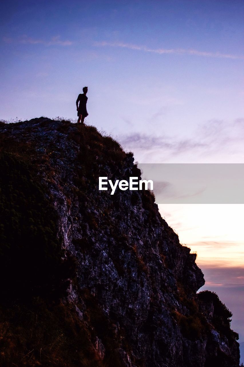 Low angle view of man standing on mountain against sky