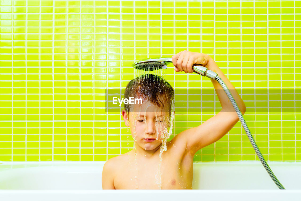 Disgusted expression of a young boy taking a shower and washing himself angrily.