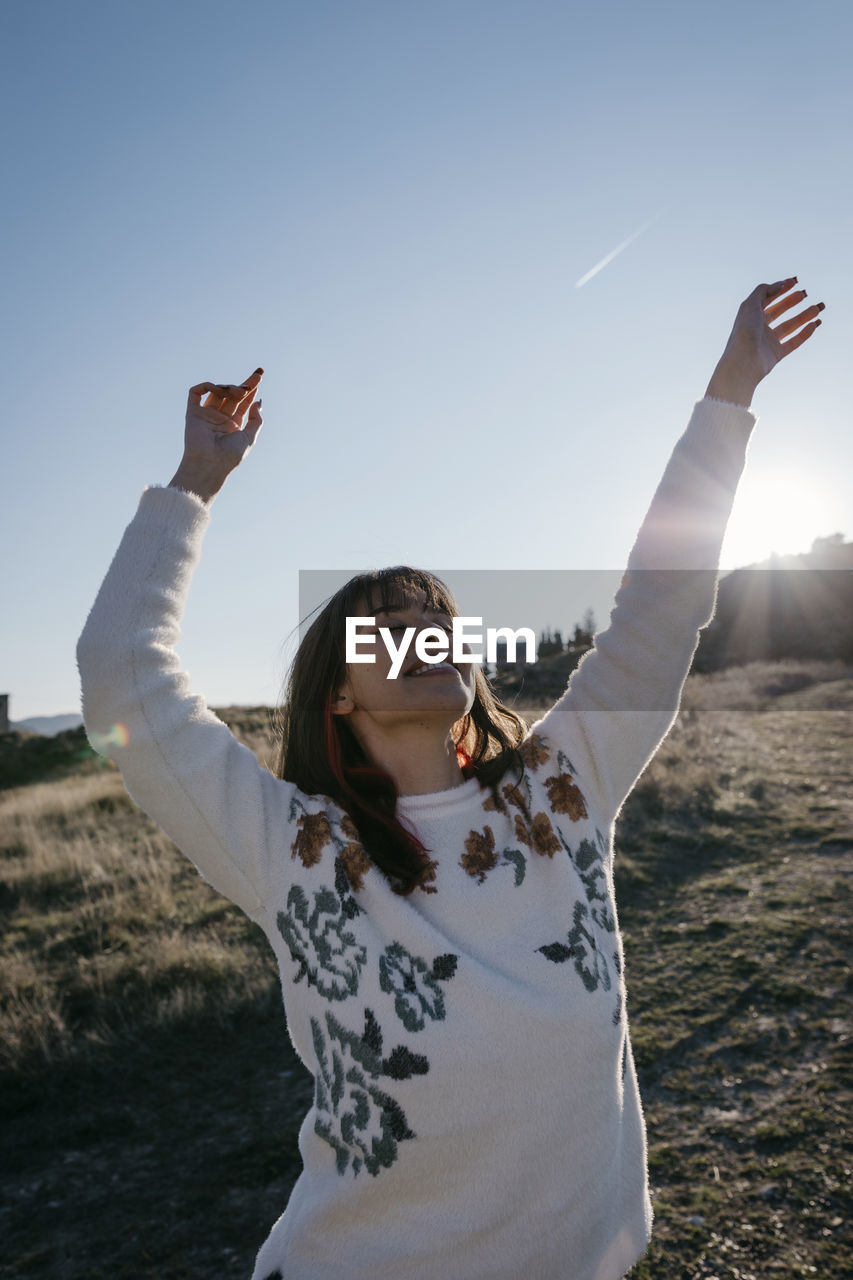 Happy woman with arms raised spending leisure time on mountain