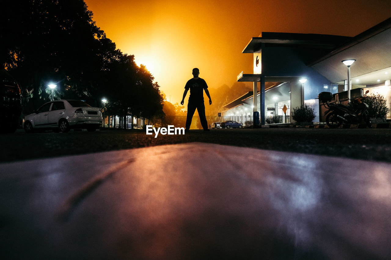 Silhouette of man standing on street at sunset