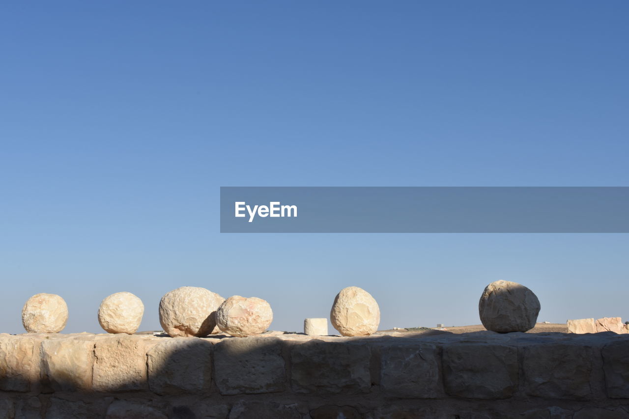 Low angle view of rocks against clear blue sky