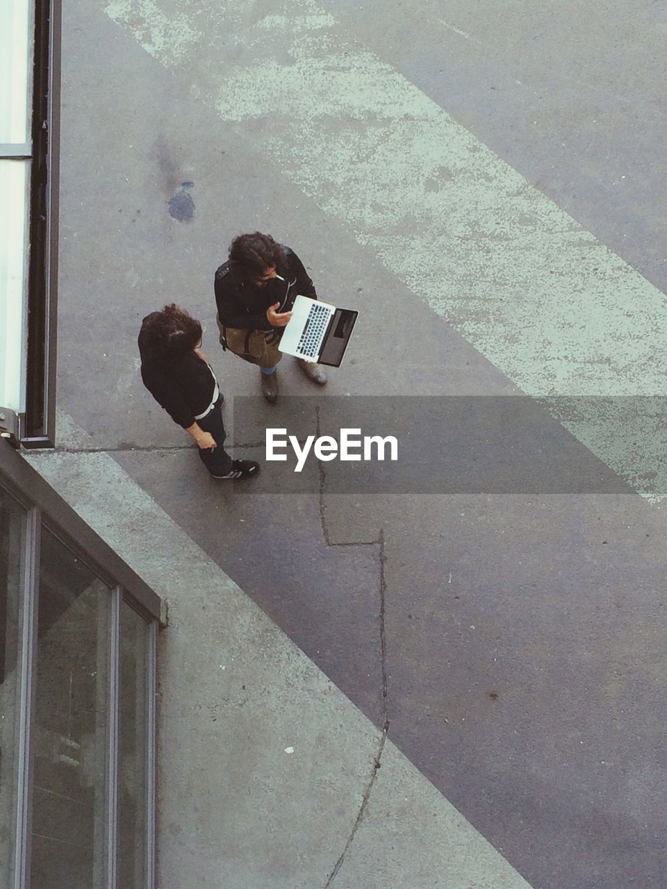 High angle view of men standing with laptop on sidewalk