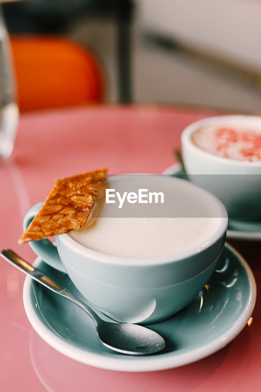 Two delicious cups of cappuccino latte with foam on the pink table in the cafe for breakfast