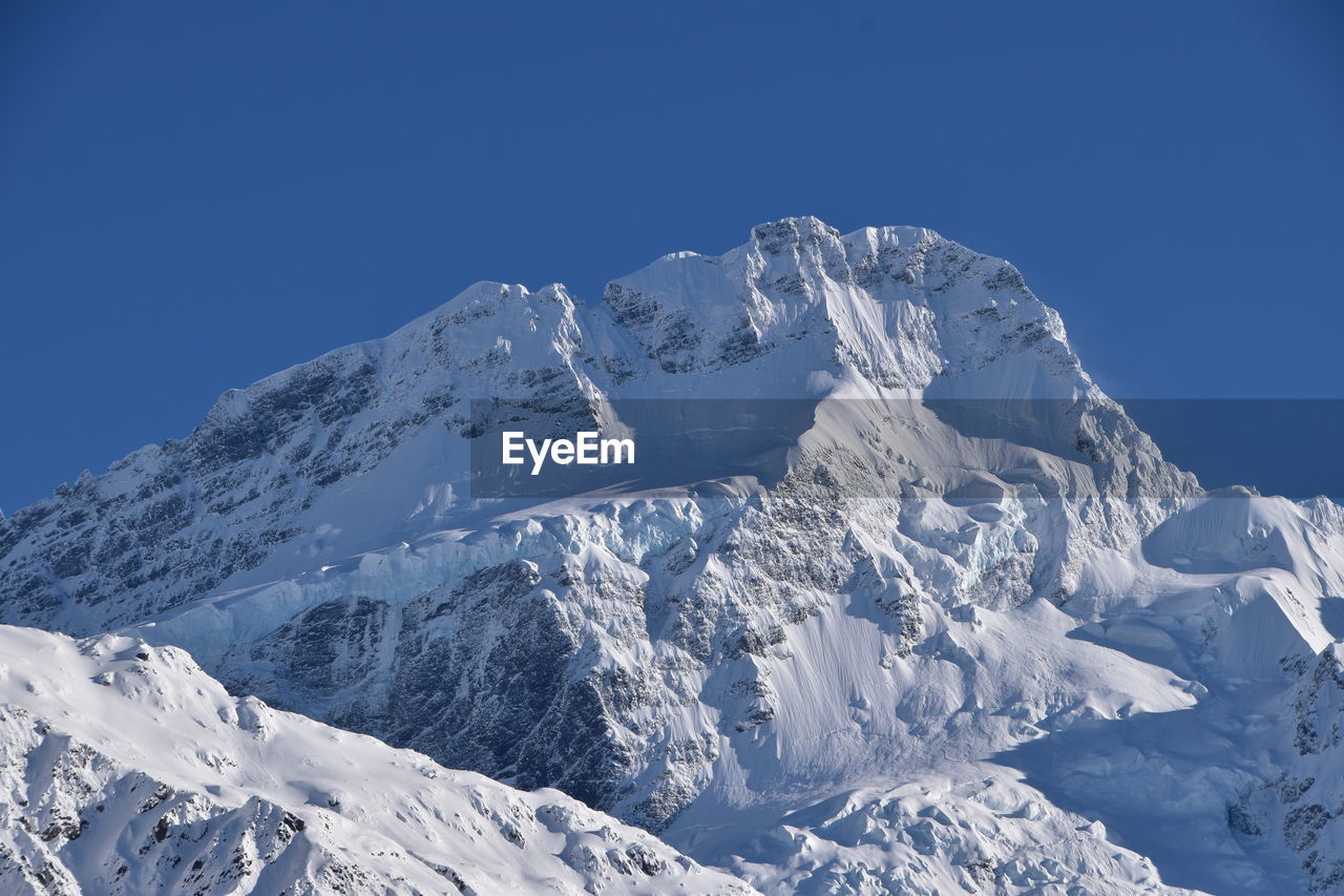 Scenic view of snowcapped mountains against clear blue sky