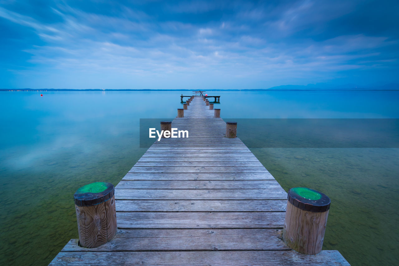 Wooden jetty on pier over sea against sky