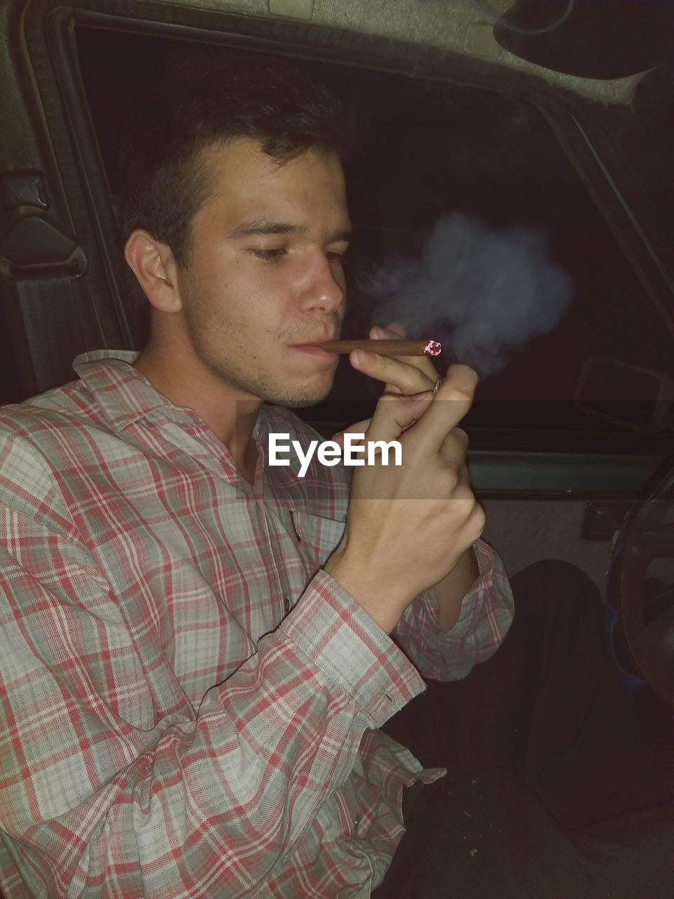 YOUNG MAN SMOKING WHILE LOOKING AT HOME