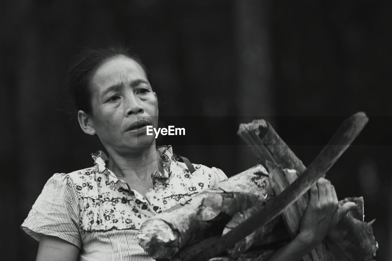 Close-up of mature woman carrying firewood