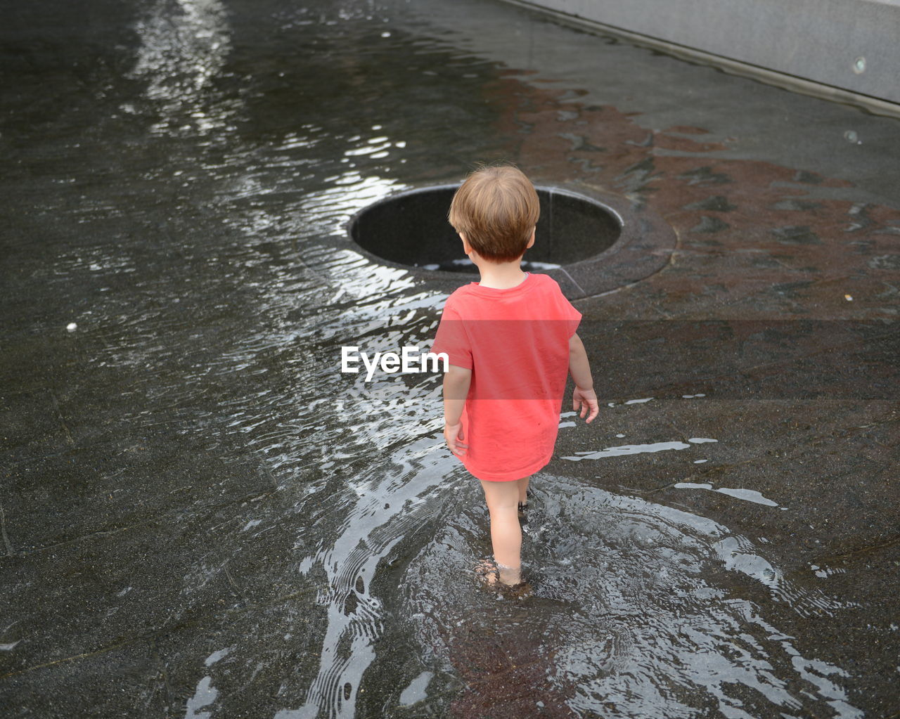 Rear view of boy standing in water