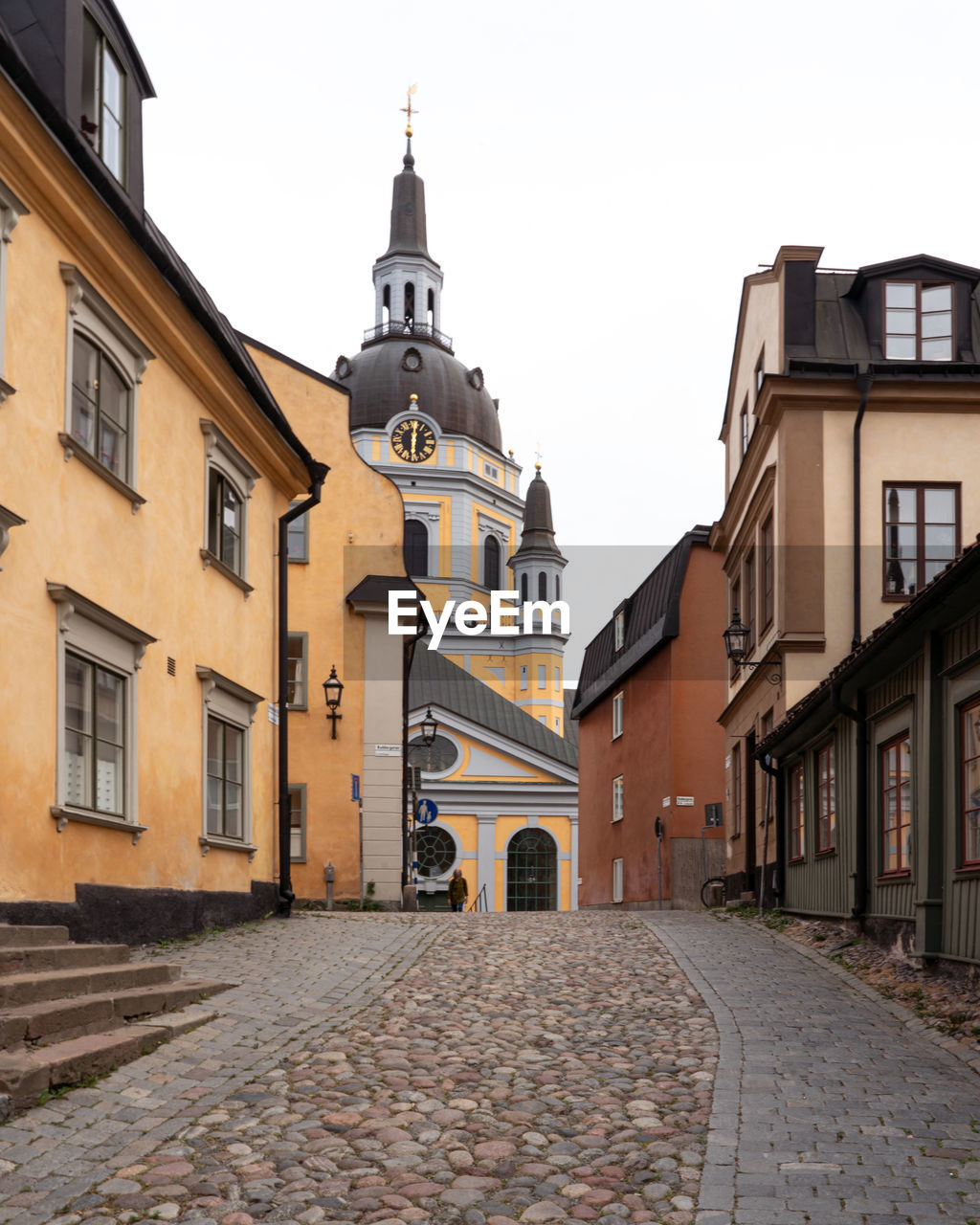 STREET AMIDST BUILDINGS IN CITY AGAINST SKY