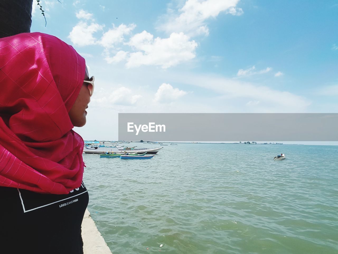 Woman wearing hijab standing by sea against sky