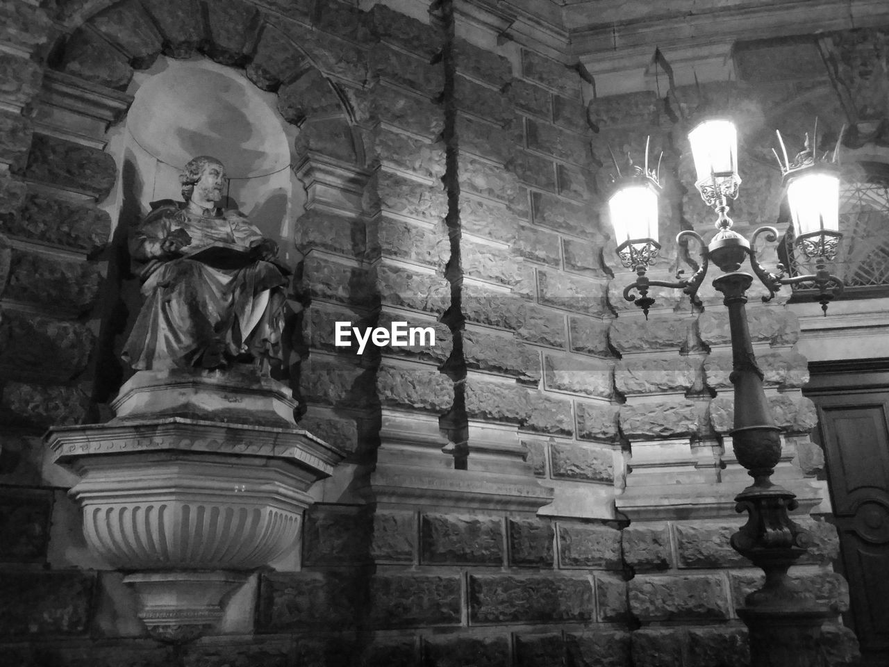 Low angle view of statue by illuminated lamp post against historic building