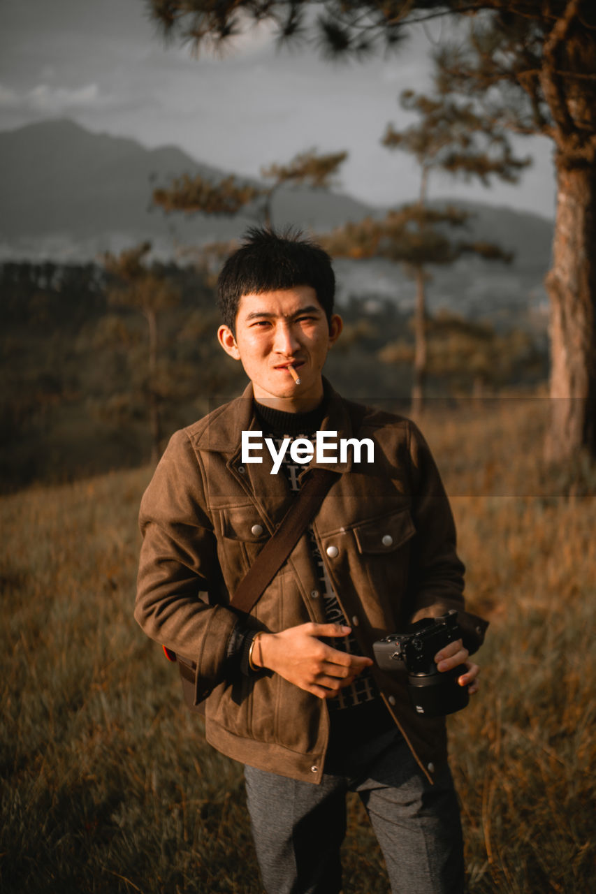 YOUNG MAN PHOTOGRAPHING IN FIELD