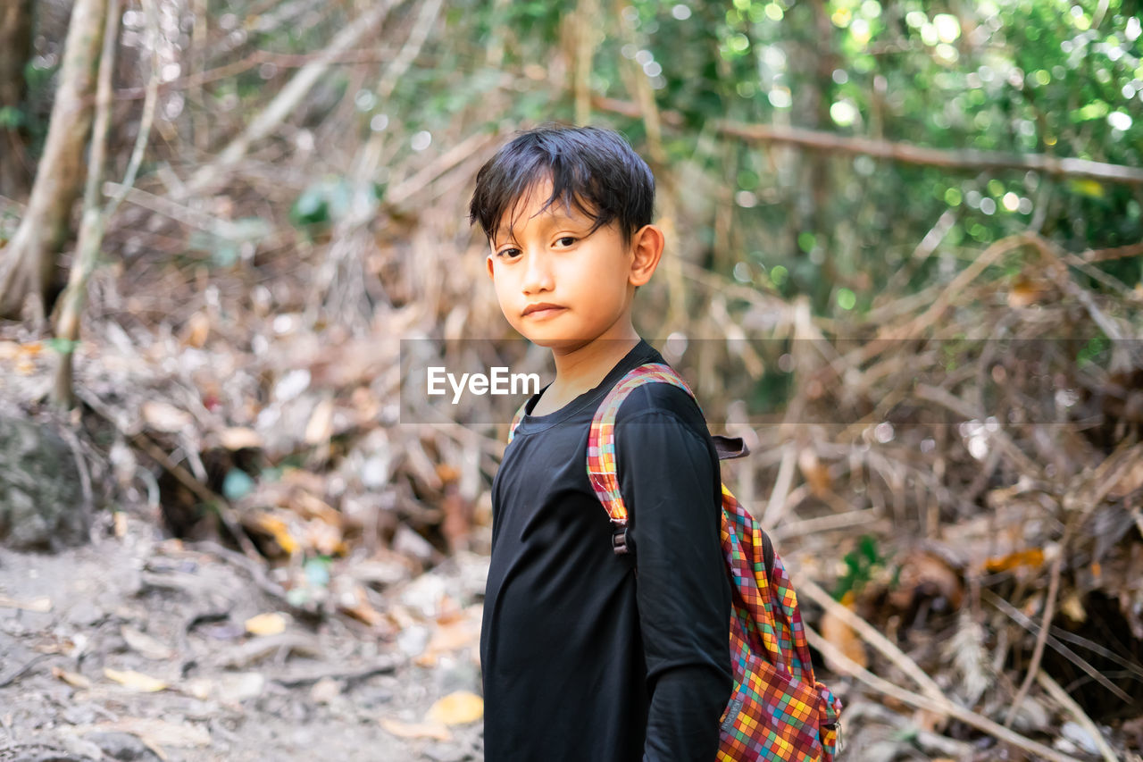 Portrait of boy standing on land in forest