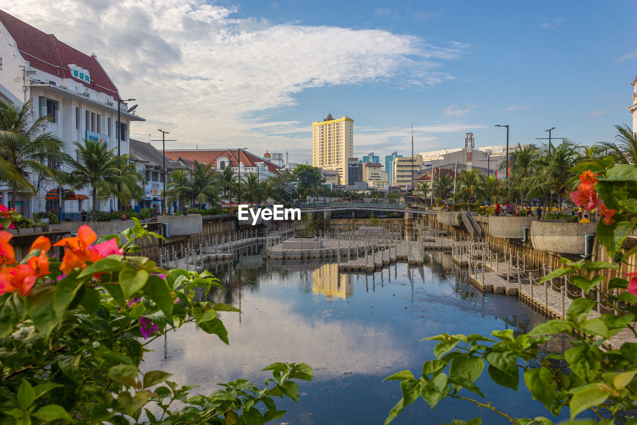 Buildings by river against sky