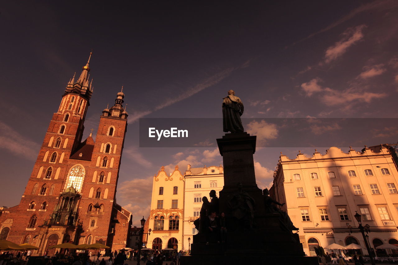 Low angle view of adam mickiewicz monument with st mary basilica against sky
