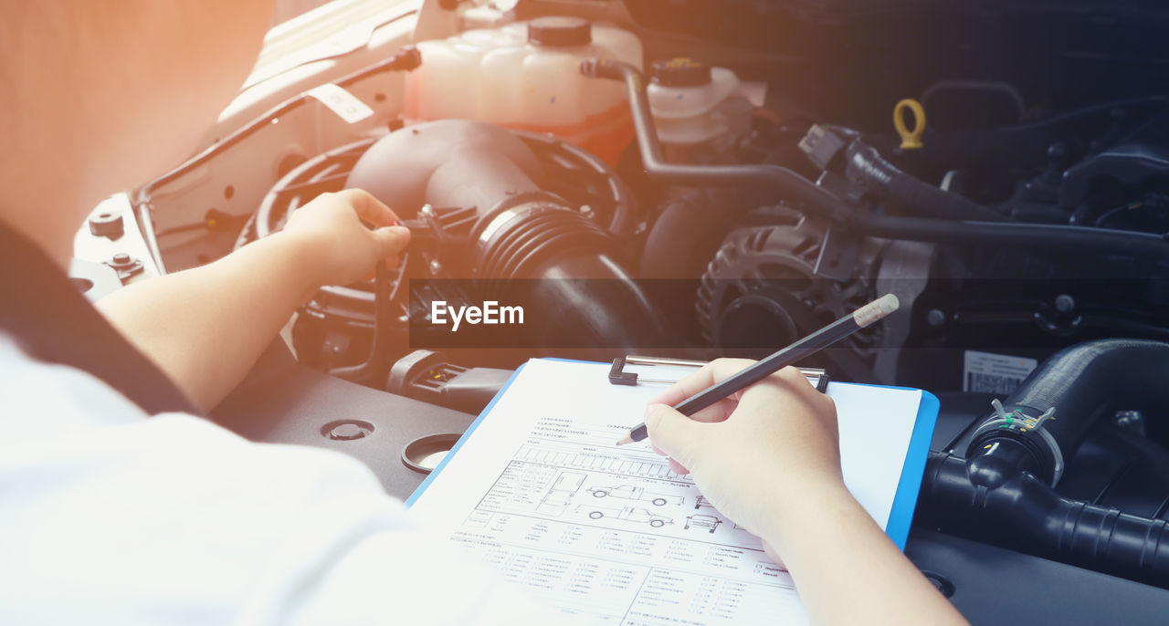 High angle view of mechanic writing in paper at auto repair shop