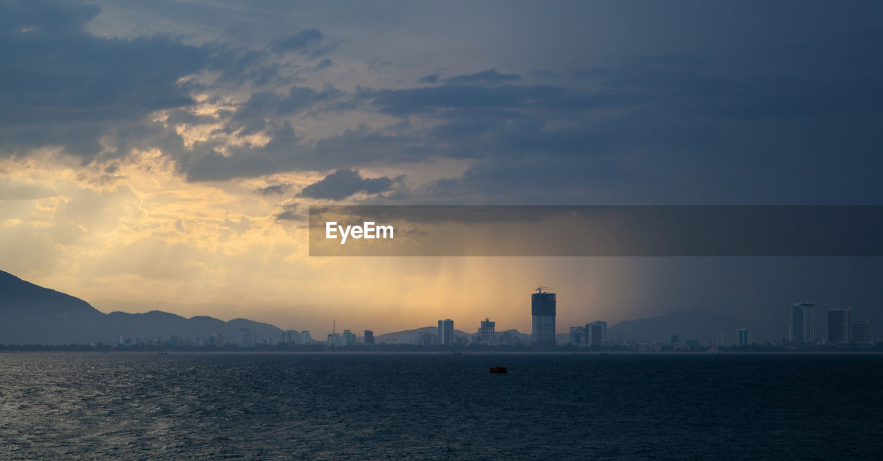 Scenic view of sea and buildings against sky during sunset