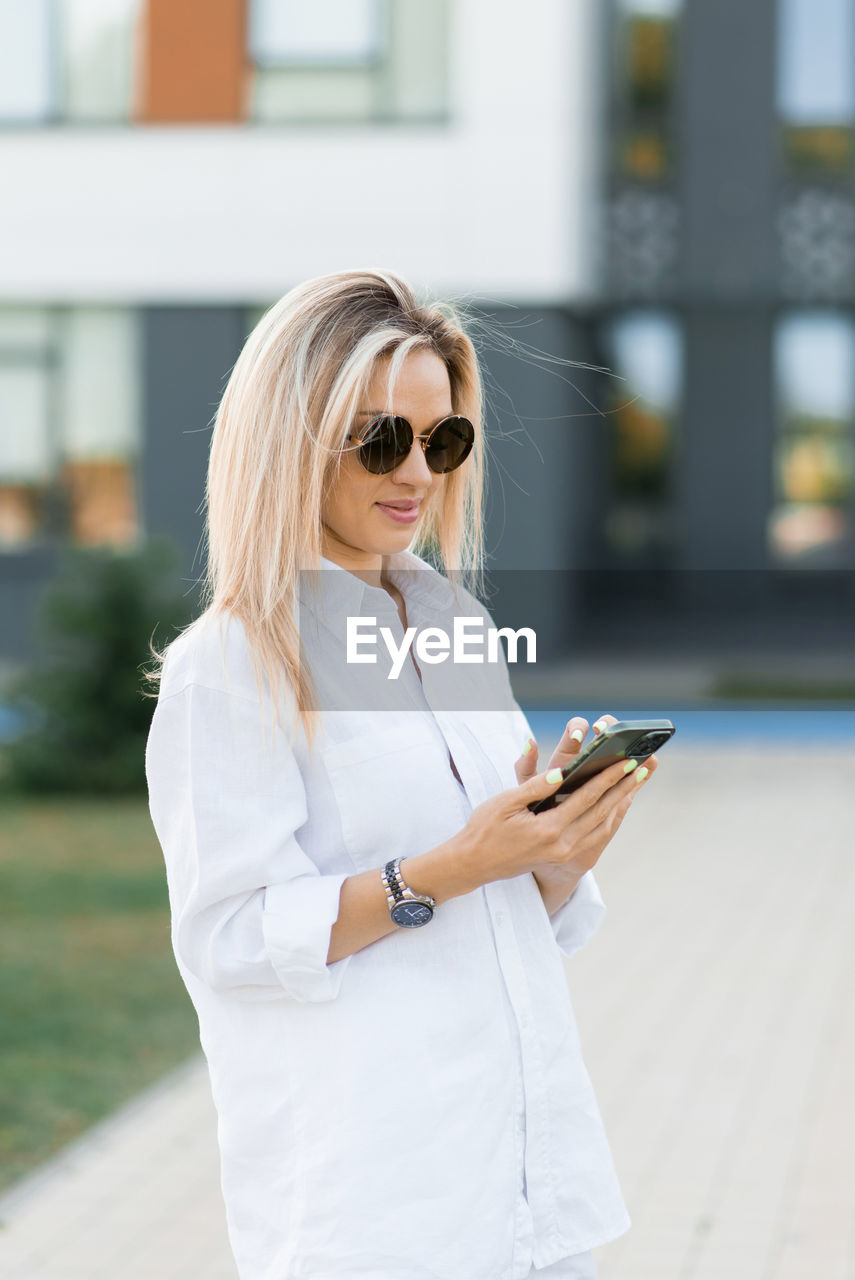 Young woman walking and using a smart phone on a city street