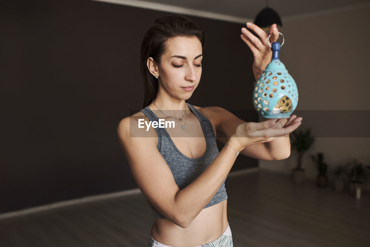 Young woman meditates alone in yoga studio with aroma lamp