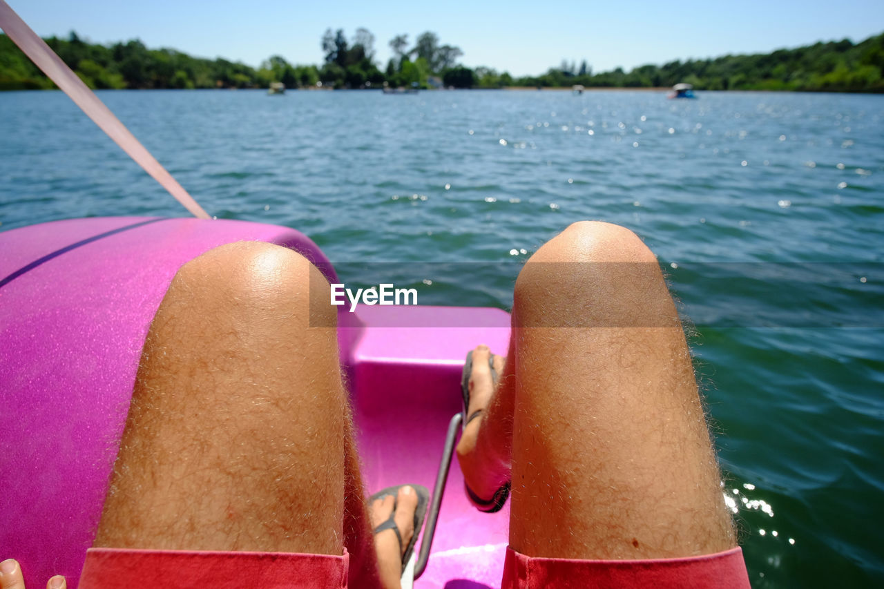 Low section of man in pedal boat on lake