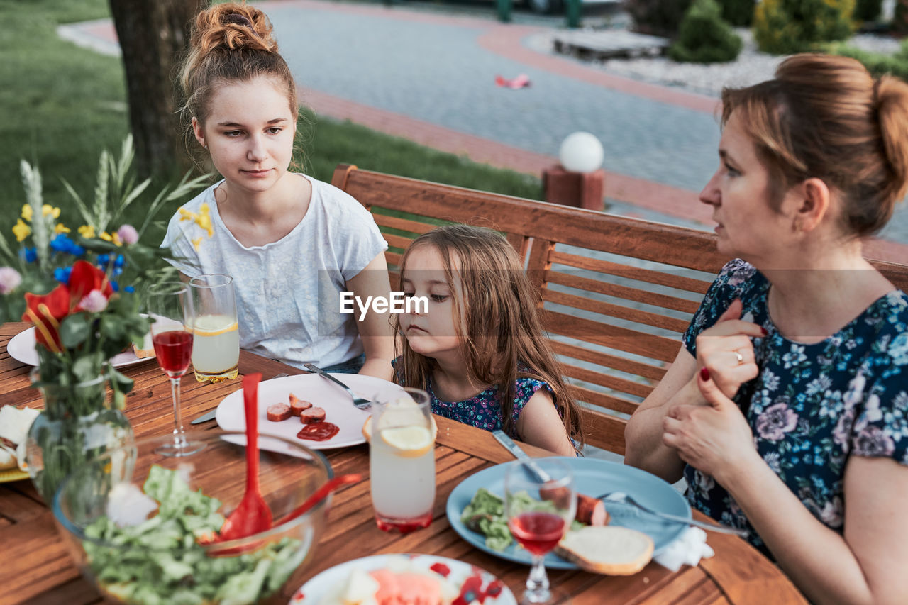 Family having a meal from grill during summer picnic outdoor dinner in a home garden