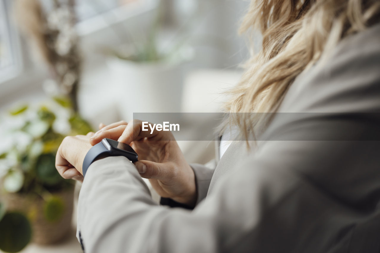 Businesswoman checking smart watch in office